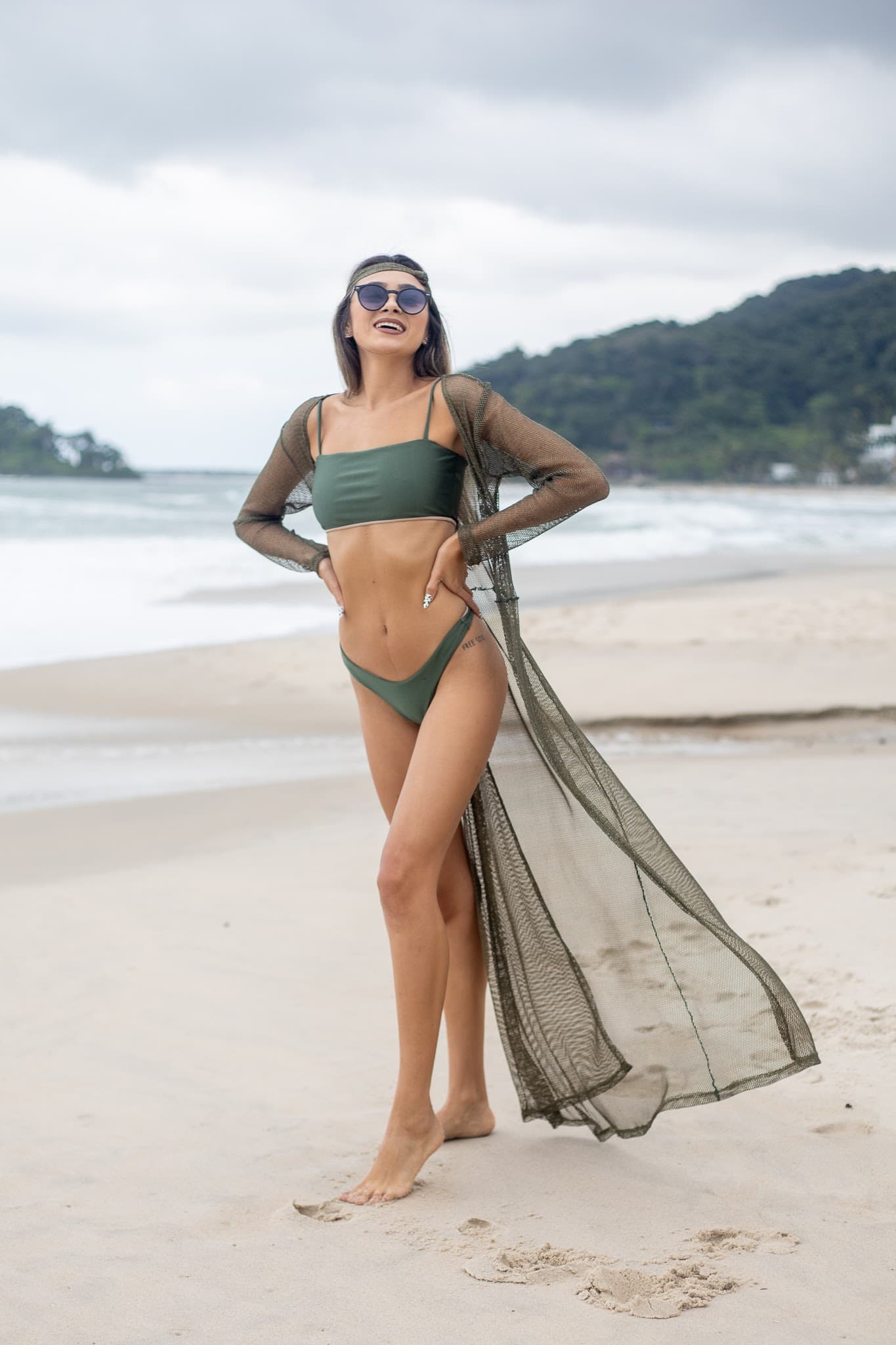 Julia Jones modeling an olive swim look and sheer cover-up on a beach