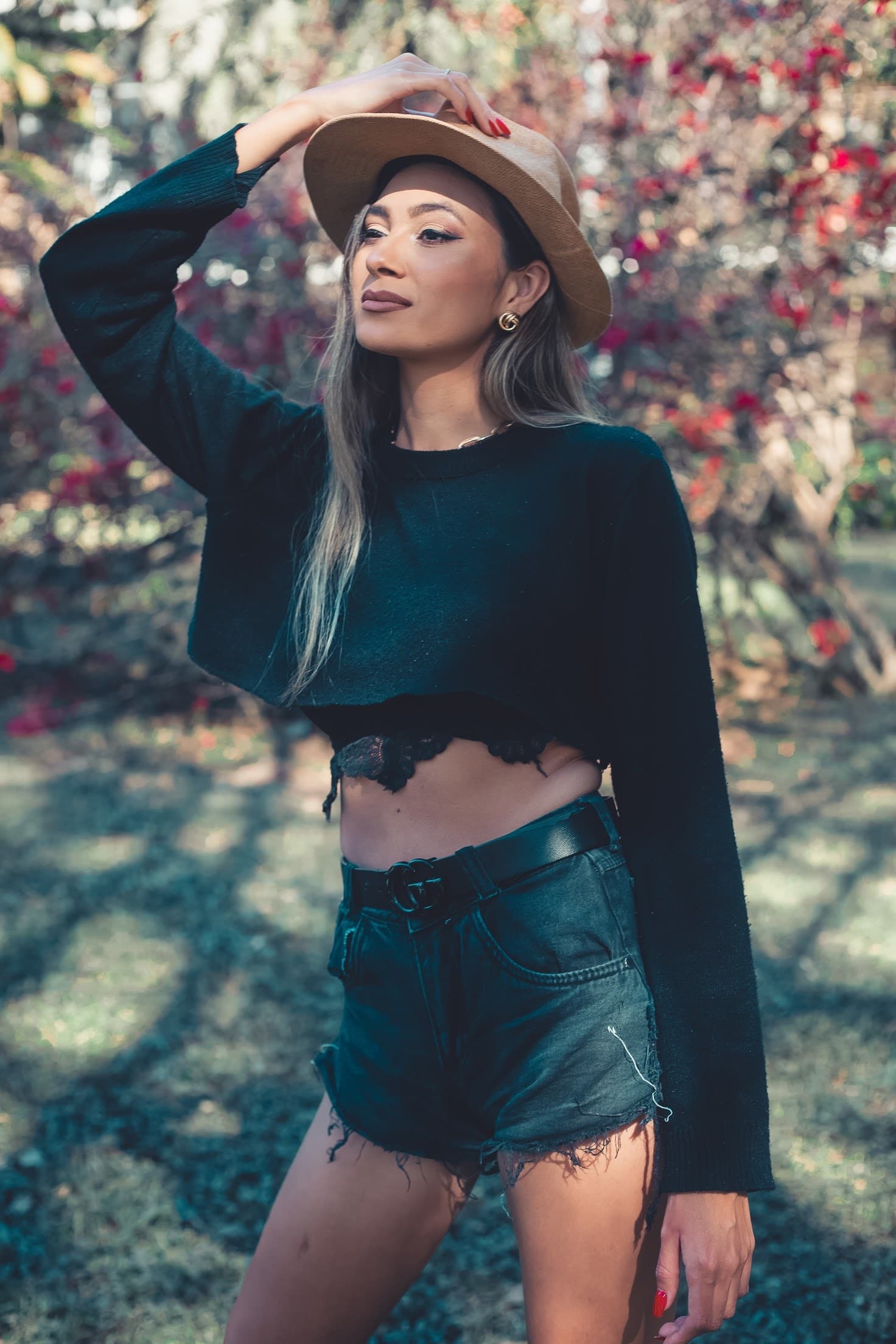 Julia Jones modeling a dark fashion look and tan hat in a garden setting