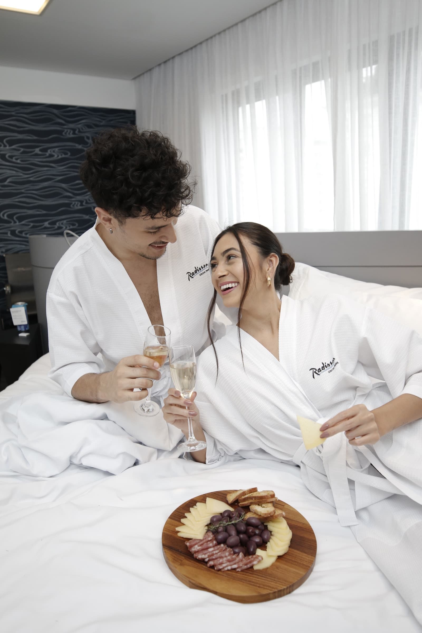 Julia Jones and a guest enjoying champagne and a charcuterie board during a Radisson stay