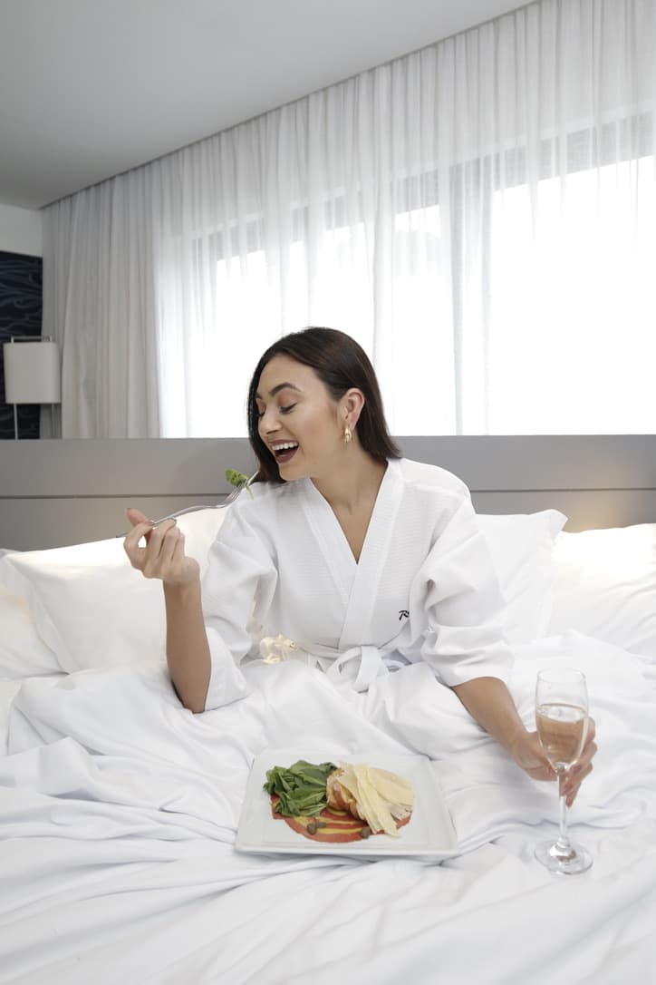 Julia Jones enjoying room service in bed during a Radisson stay campaign