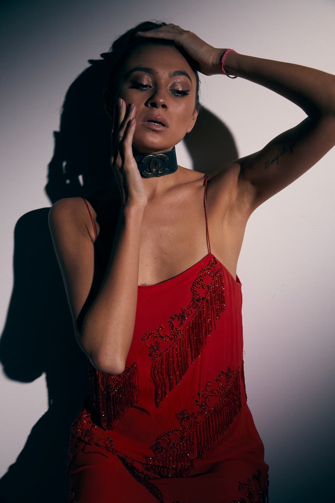 Julia Jones modeling a red fringed look and statement choker in dramatic beauty lighting