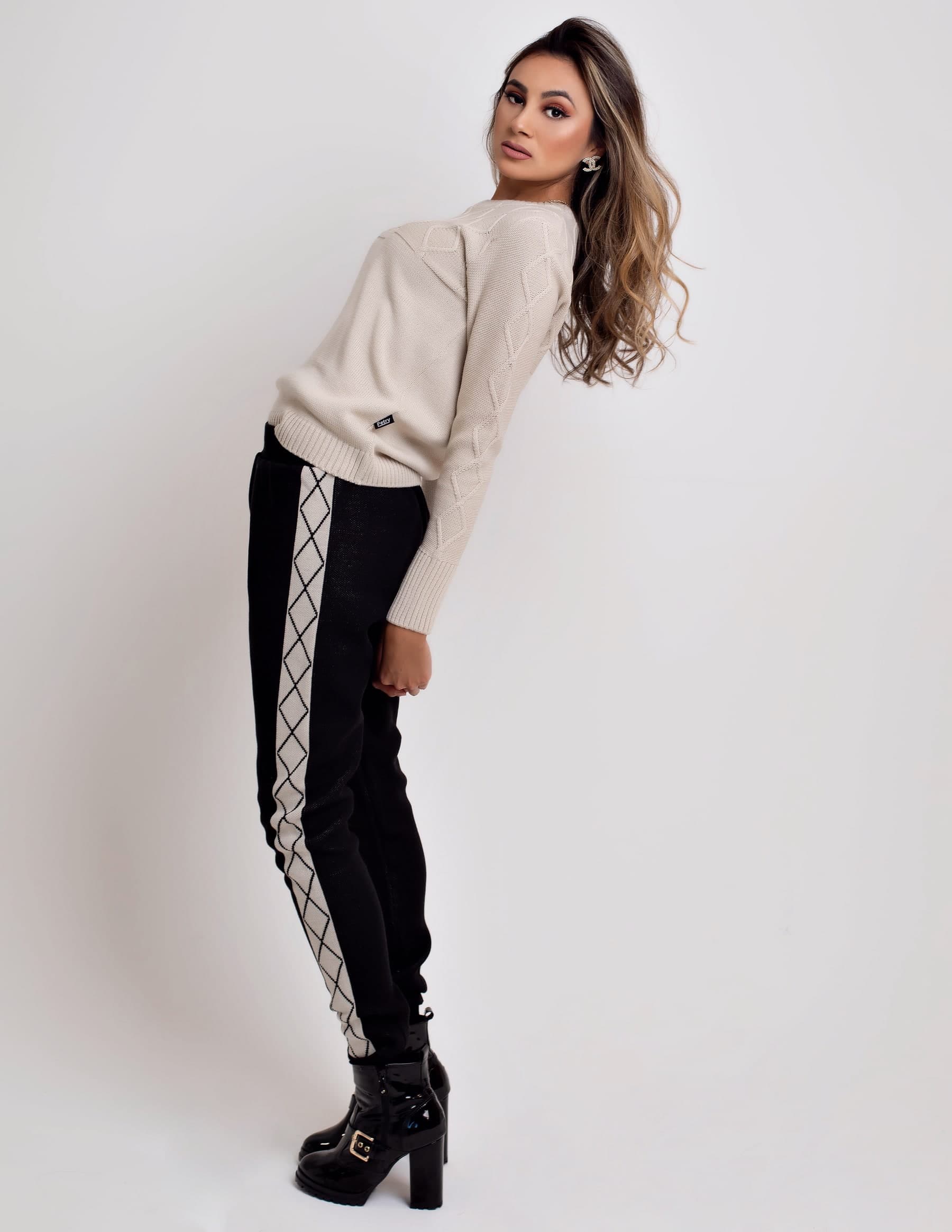 Julia Jones modeling a neutral knit top and black patterned pants in a studio portrait